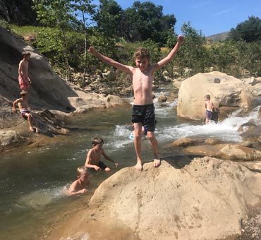 Kids playing on rocks in a river.