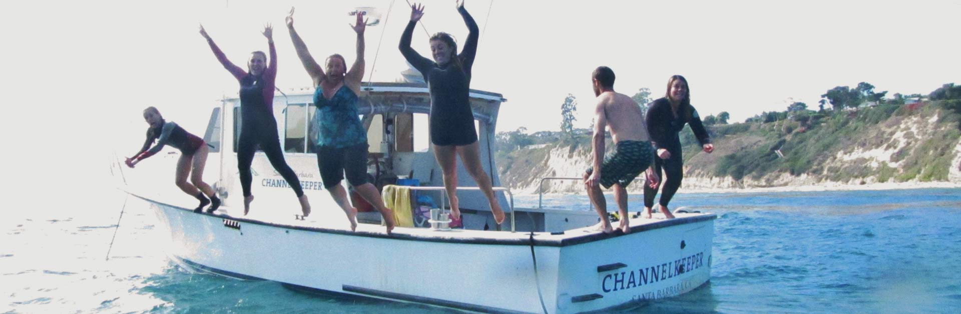 A happy group of Santa Barbara Channelkeeper members jumping off the R/V Channelkeeper boat.